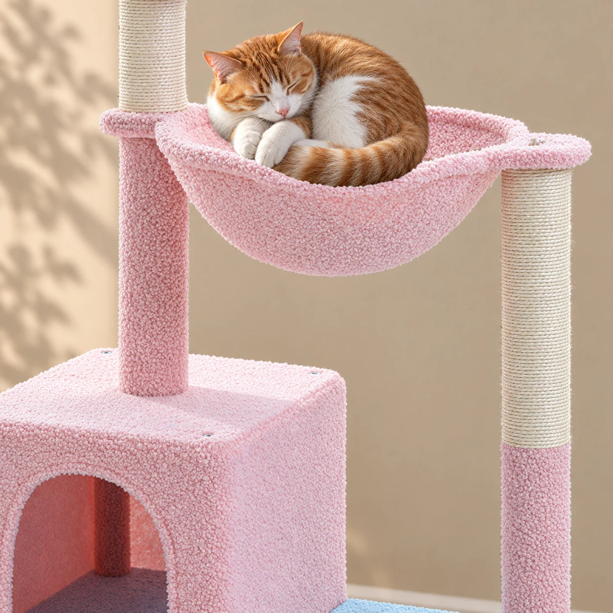 Gros plan d’un chat roux endormi dans le hamac rose de l’arbre à chat Cornflower