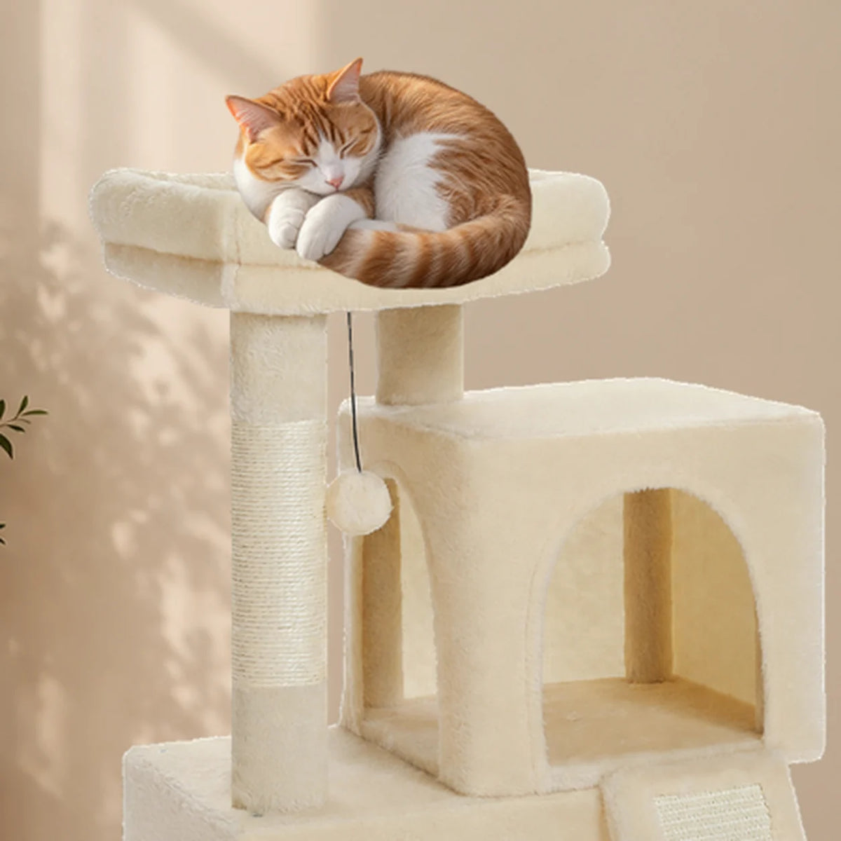 Gros plan d’un chaton roux endormi sur le perchoir rembourré de l’arbre à chat Bramley